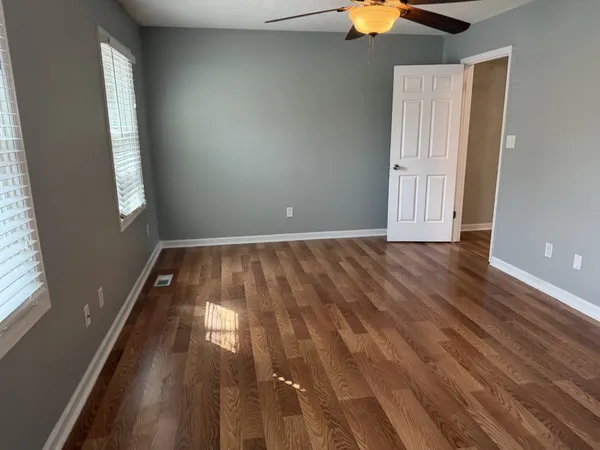 a view of empty room with wooden floor and fan