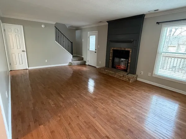 an empty room with wooden floor fireplace and windows