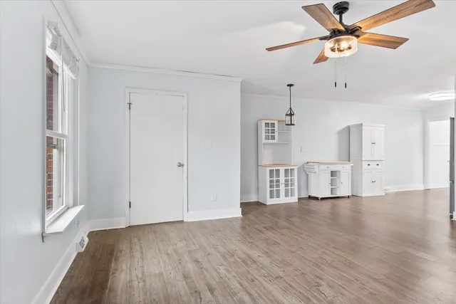 a view of empty room with wooden floor and fan