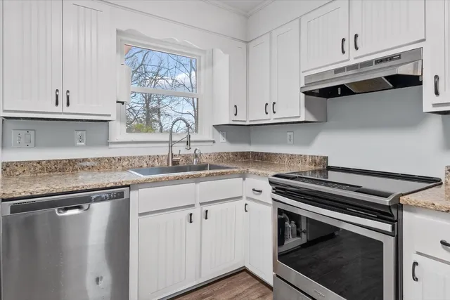 a kitchen with granite countertop a stove sink and cabinets
