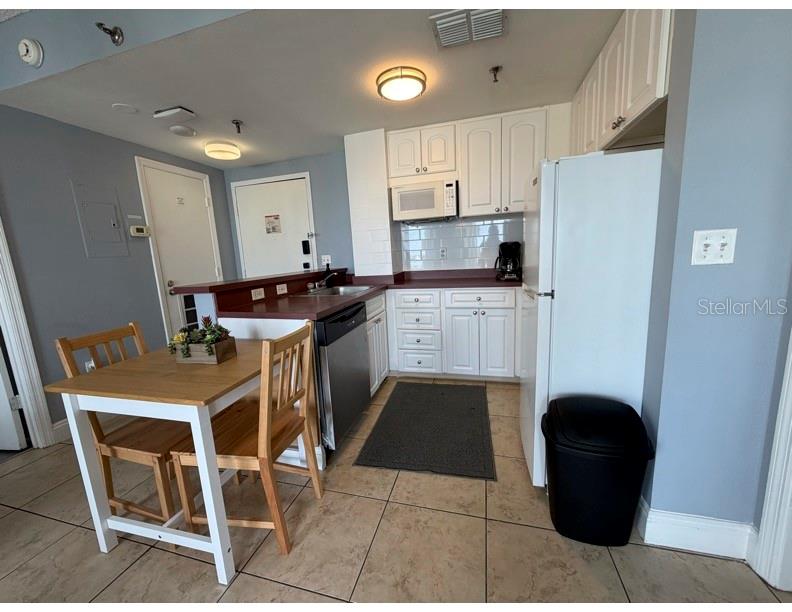 6165 Carrier Drive, Unit 1903 Orlando, FL 32819 - Photo 5 of 21 a kitchen with stainless steel appliances granite countertop a stove a refrigerator a sink a dining table and chairs