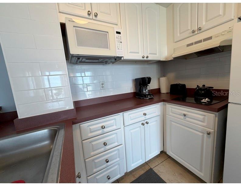 6165 Carrier Drive, Unit 1903 Orlando, FL 32819 - Photo 6 of 21 a kitchen with white cabinets and sink