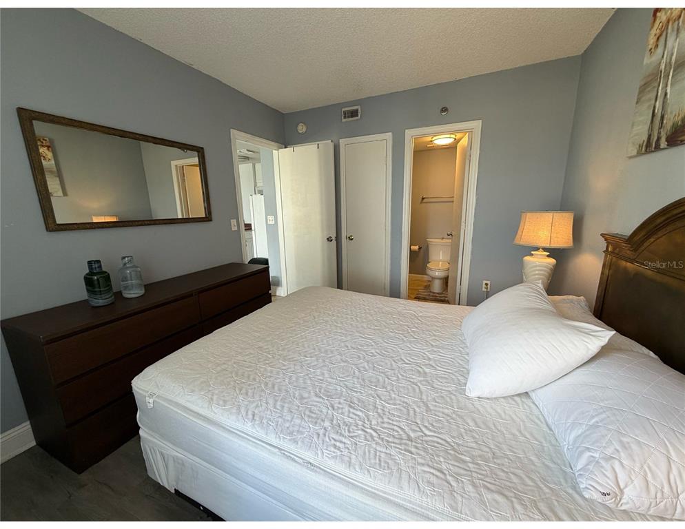 6165 Carrier Drive, Unit 1903 Orlando, FL 32819 - Photo 8 of 21 a bedroom with a bed and a lamp on dresser