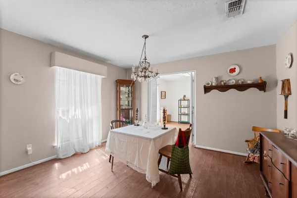a dining room with wooden floor and chandelier