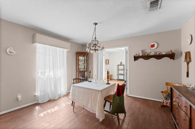 a dining room with wooden floor and chandelier