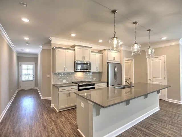 a kitchen with kitchen island granite countertop a sink cabinets and stainless steel appliances