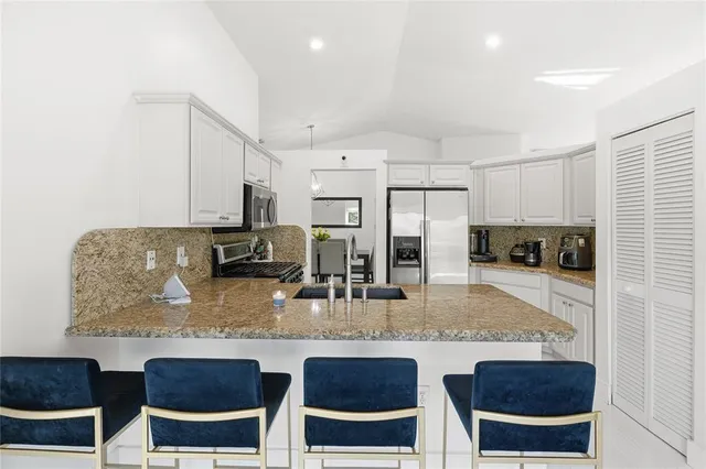 a kitchen with stainless steel appliances granite countertop a table chairs sink and cabinets