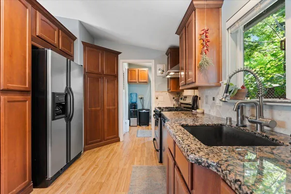 a kitchen with granite countertop a sink stainless steel appliances and cabinets