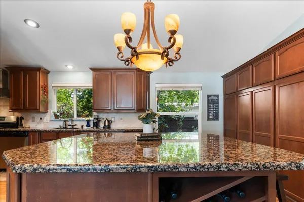 a kitchen with kitchen island granite countertop a sink a counter top space and living room view
