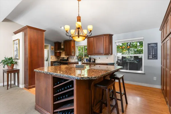 a kitchen with stainless steel appliances granite countertop a sink a stove and a wooden floors