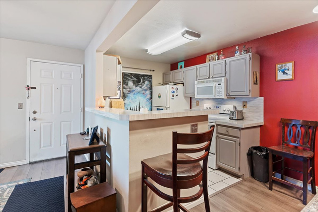 650 South Main Street, Unit 4104 Bountiful, UT 84010 - Photo 8 of 22 Kitchen with light countertops, backsplash, gray cabinets, and a breakfast bar