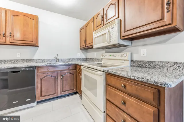 a kitchen with granite countertop stainless steel appliances white cabinets sink and dishwasher