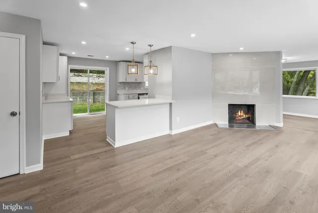 a room with kitchen island a sink wooden floor and a fireplace
