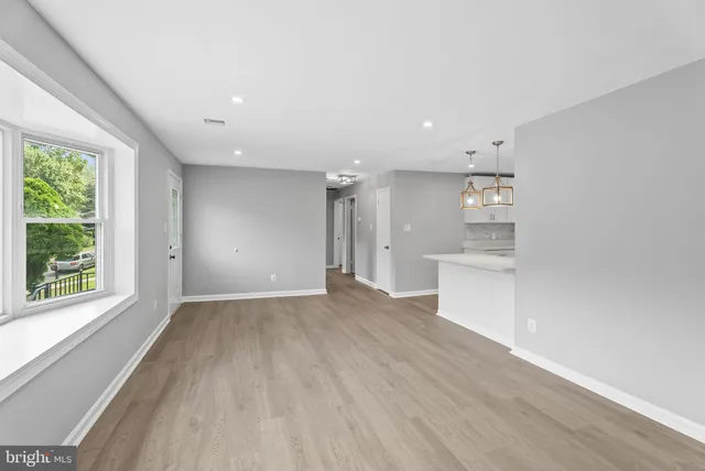 a view of an empty room with a window and wooden floor