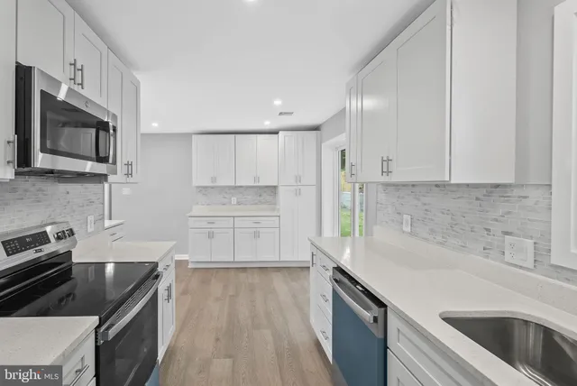 a kitchen with granite countertop a sink dishwasher stove and cabinets with wooden floor