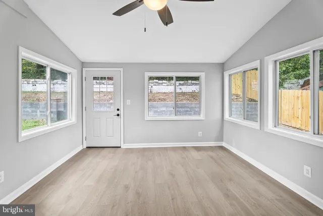 a view of an empty room with wooden floor and a window