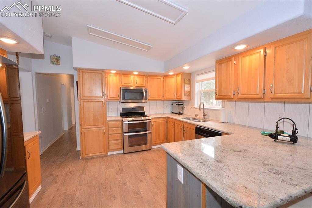 123 Pawutsy Road Florissant, CO 80816 - Photo 10 of 30 a kitchen with stainless steel appliances granite countertop a sink a refrigerator and wooden cabinets