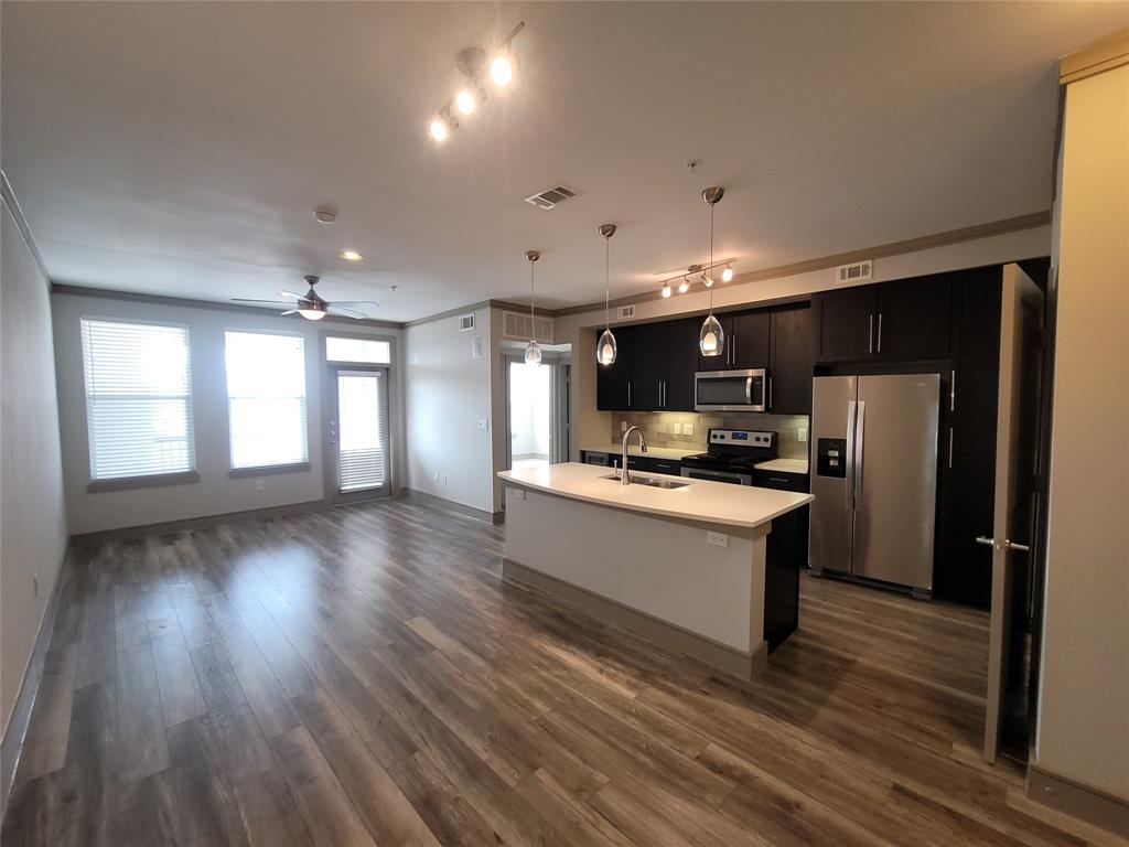 a large white kitchen with wooden floor and stainless steel appliances