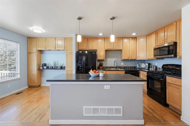 a kitchen with kitchen island granite countertop a sink a counter top space appliances and cabinets