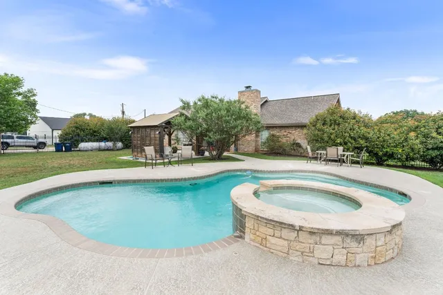 a view of swimming pool with outdoor seating and house in the background