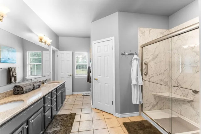 a bathroom with a double vanity sink a mirror and a shower