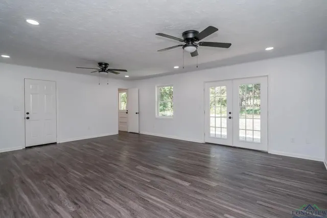 a view of an empty room with a window and wooden floor