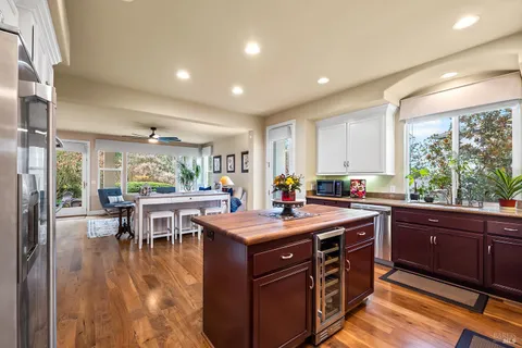 a kitchen with stainless steel appliances granite countertop a refrigerator a sink a stove a dining table and chairs