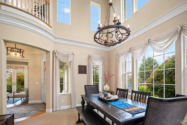 a open kitchen with granite countertop a refrigerator a stove a dining table and chairs with wooden floor