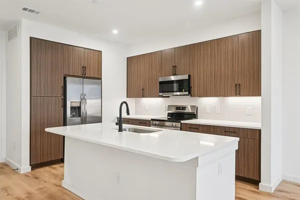 a kitchen with stainless steel appliances a sink a stove a microwave a sink a refrigerator and cabinets