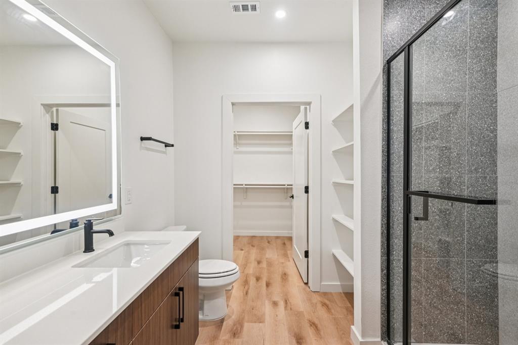 2016 South Ervay Street, Unit B1 Dallas, TX 75215 - Photo 19 of 35 Bathroom featuring a spacious closet, vanity, light wood-style floors, and a shower stall