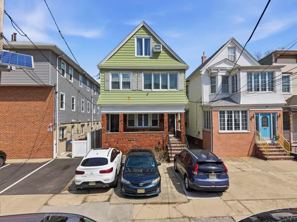a front view of a house with cars parked