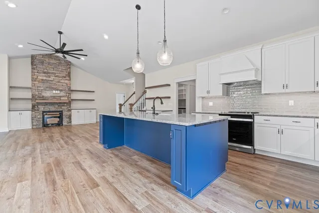 a kitchen with stainless steel appliances kitchen island granite countertop a stove a sink and a wooden floors