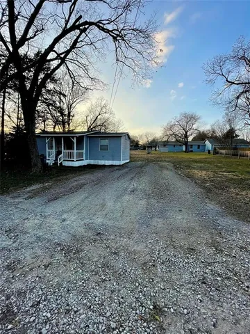 a view of a house with a yard and a large tree