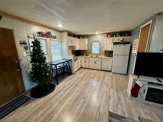 a kitchen with stainless steel appliances a refrigerator a sink a stove a microwave a refrigerator and wooden floor