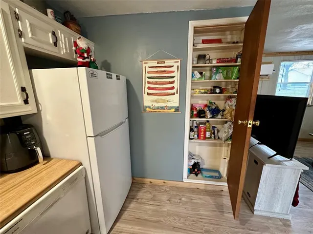 a view of a kitchen with fridge and wooden floor