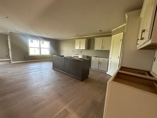 a room with kitchen island a sink a stove and cabinets