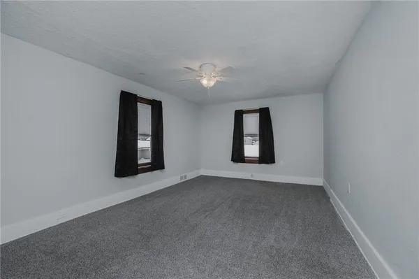 an empty room with windows and ceiling fan