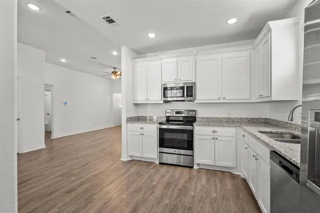 a kitchen with granite countertop white cabinets and stainless steel appliances