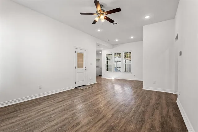 a view of an empty room with window and wooden floor