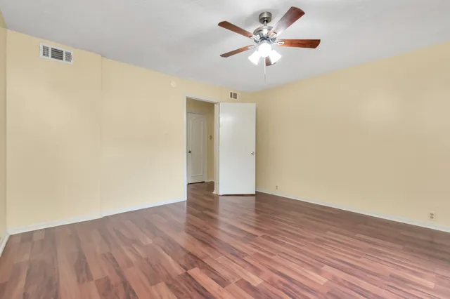 an empty room with wooden floor and a ceiling fan