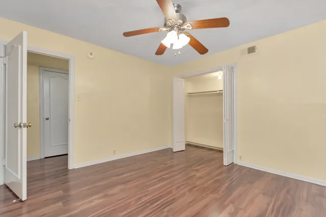 an empty room with wooden floor chandelier fan and closet area