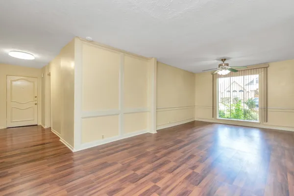 an empty room with wooden floor and windows