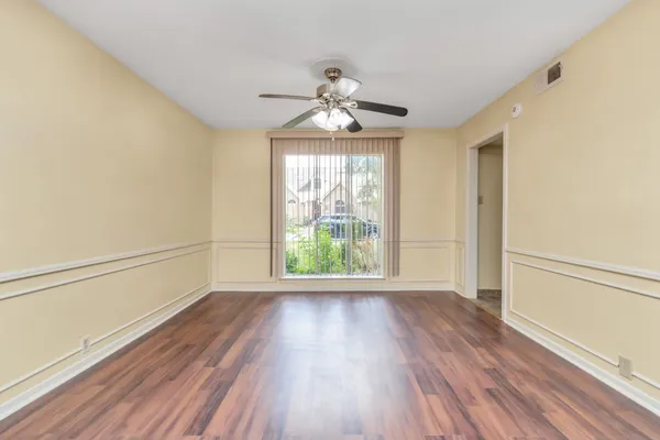 a view of empty room with wooden floor and fan