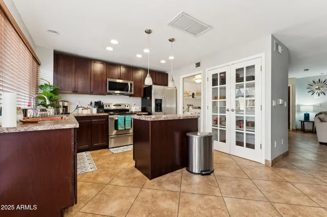 a kitchen with stainless steel appliances granite countertop a refrigerator a sink a stove top oven and a dining table