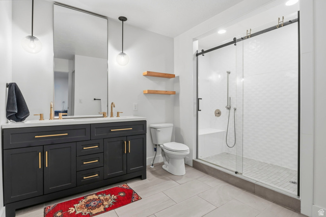 4150 Dover Lane Provo, UT 84604 - Photo 18 of 44 Modern bathroom featuring a double vanity with dark cabinetry, gold-finish hardware, and a light-toned countertop