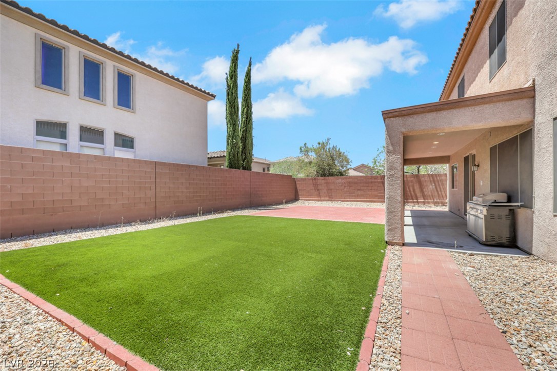 2501 Bechamel Place Henderson, NV 89044 - Photo 47 of 50 A low-maintenance backyard oasis features artificial turf and a shaded patio for outdoor leisure.