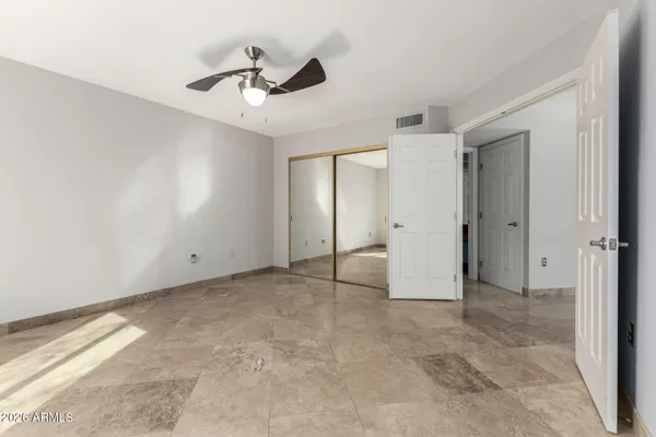 an empty room with chandelier fan and windows