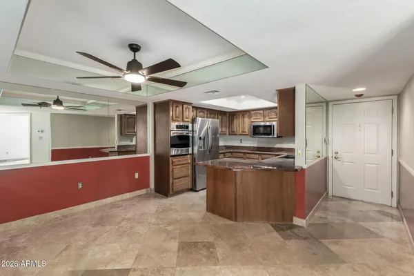 a large kitchen with stainless steel appliances kitchen island granite countertop a refrigerator and a sink