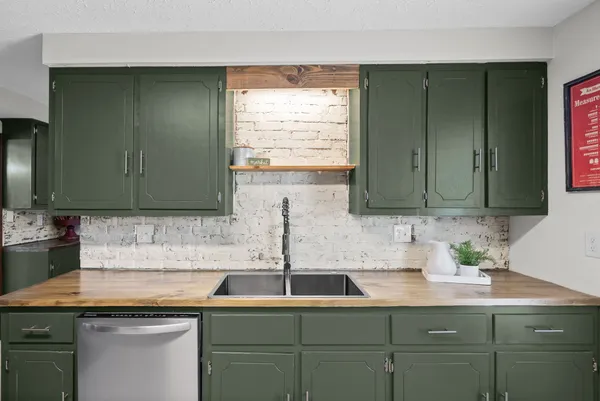 a kitchen with stainless steel appliances granite countertop a refrigerator a stove a sink a dining table and chairs with wooden floor
