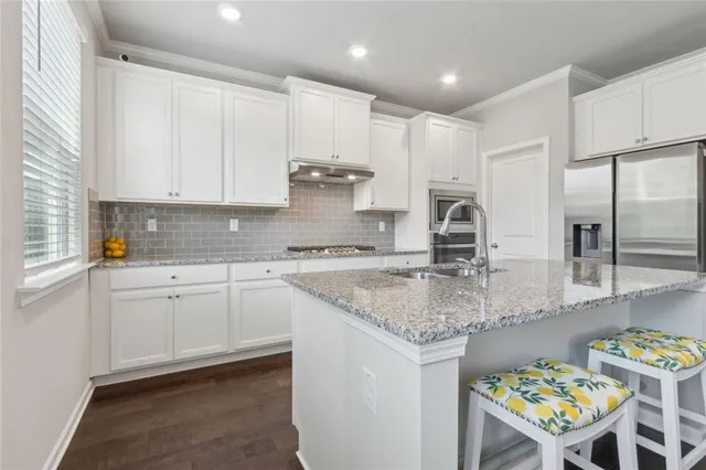 a kitchen with stainless steel appliances granite countertop a table chairs sink and cabinets
